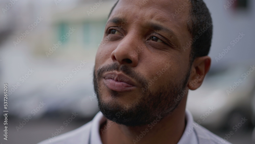 Fototapeta premium One anxious young African American man in distress closeup face. Portrait of a black person with worried preoccupied emotion