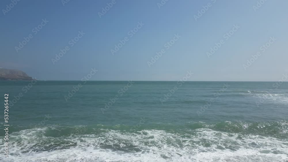 Aerial dolly shot of the beach in miraflores lima peru facing the turquoise water with a swimmer going into the water on a sunny cloudless day Aerial dolly shot of the beach in miraflores lima peru facing the turquoise water with a swimmer going into the water on a sunny cloudless day