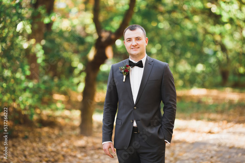 Happy handsome smiling groom posing with boutonniere photo