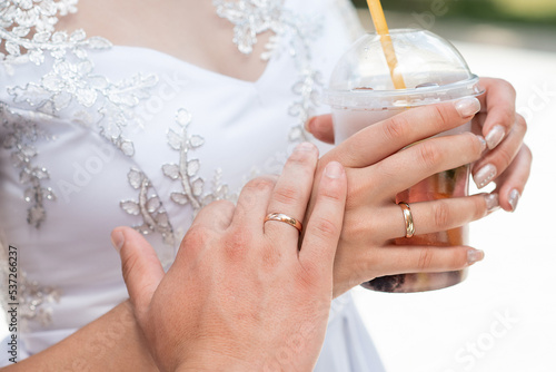 newlyweds with cocktails in their hands. close-up of the hand and ring. summer drink