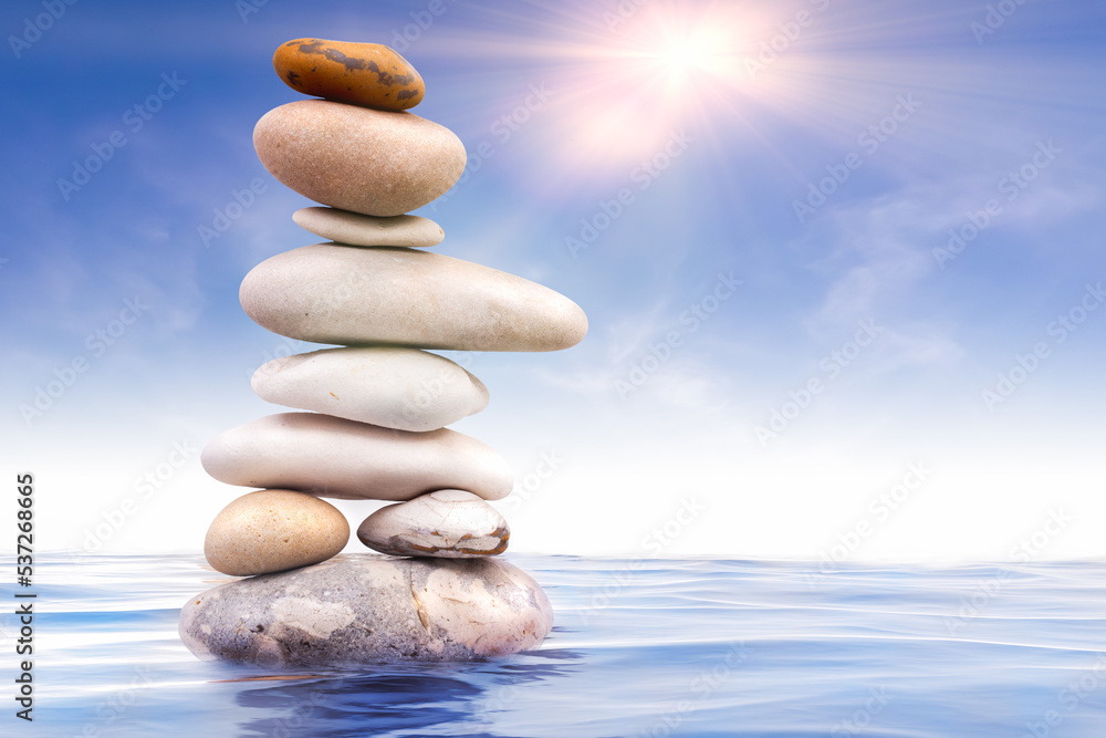 Zen stones balanced in water with sunlight