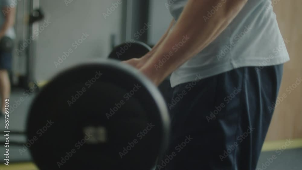 Close up shot of strong man in sportswear doing barbell bicep curls while having workout in gym Close up shot of strong man in sportswear doing barbell bicep curls while having workout in gym