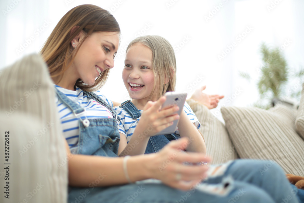 close up.happy mom and her daughter are watching videos on smartphone close up.happy mom and her daughter are watching videos on smartphone