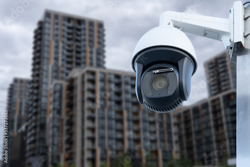 Panoramic view of CCTV surveillance camera with blurred apartment building background with copy space for background banner.