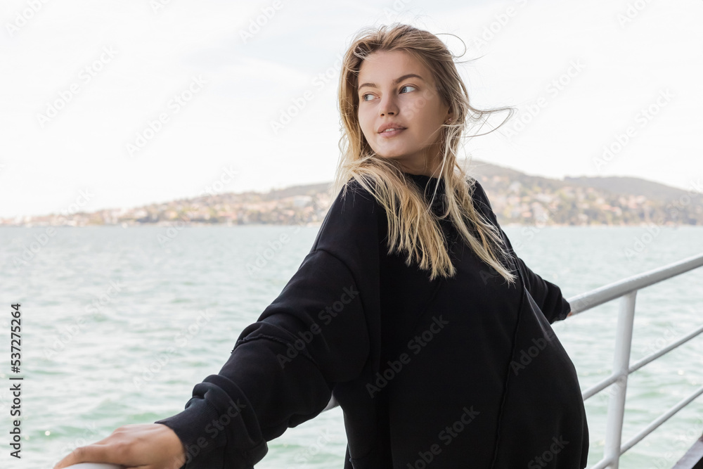 pretty woman in black sweater looking at sea from ferry boat crossing bosporus in istanbul.