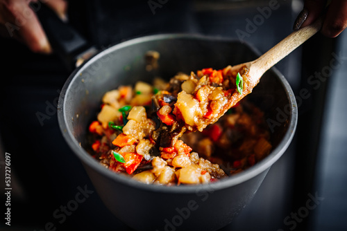 Woman cooking tasty vegetable stew in pan on kitchen