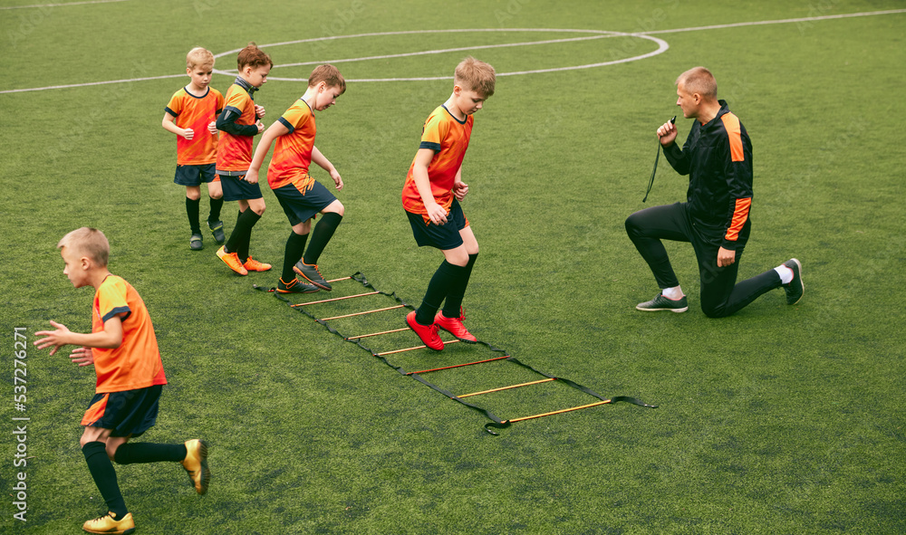Workout. Junior soccer team training with football coach at sports stadium, outdoors. Concept of sport, competition, studying and achievements Workout. Junior soccer team training with football coach at sports stadium, outdoors. Concept of sport, competition, studying and achievements