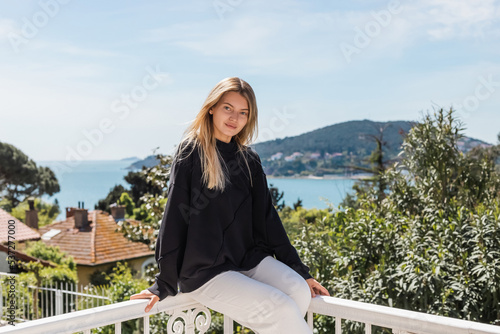 young and blonde woman posing near houses and sea on princess islands in turkey. photo