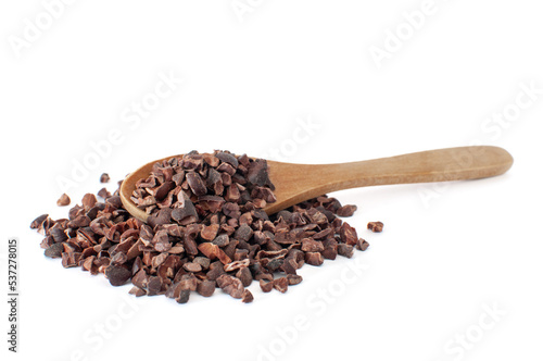 Profile view of organic raw cacao nibs pile with natural wood spoon on. Isolated on white background with selective focus.