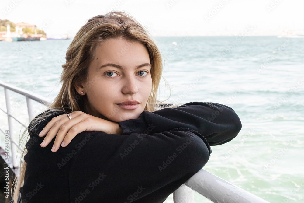young woman in black sweater looking at camera from ferry boat crossing bosporus. young woman in black sweater looking at camera from ferry boat crossing bosporus.