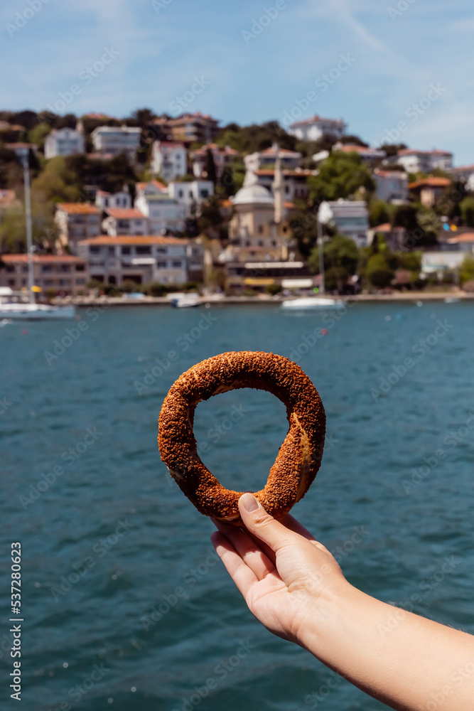 cropped view of woman holding turkish sesame bagel near sea. cropped view of woman holding turkish sesame bagel near sea.