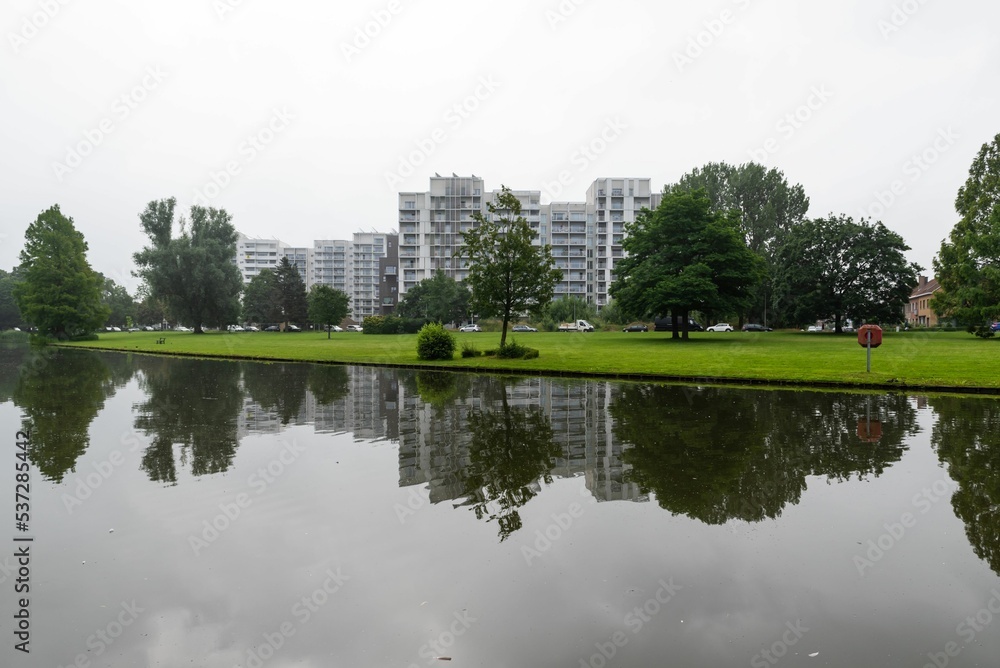 Kortrijk, West Flanders Region - Belgium -  The Raemdonck city park water pond with residential apartment blocks reflecting in the background.