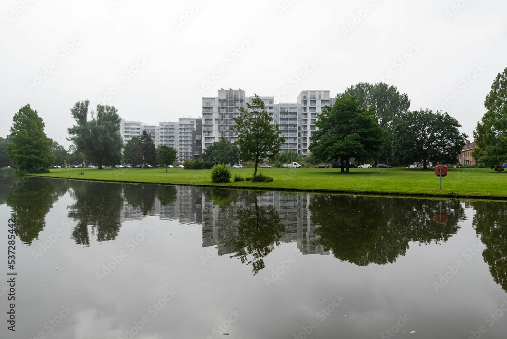 Kortrijk, West Flanders Region - Belgium - The Raemdonck city park water pond with residential apartment blocks reflecting in the background. Kortrijk, West Flanders Region - Belgium - The Raemdonck city park water pond with residential apartment blocks reflecting in the background.