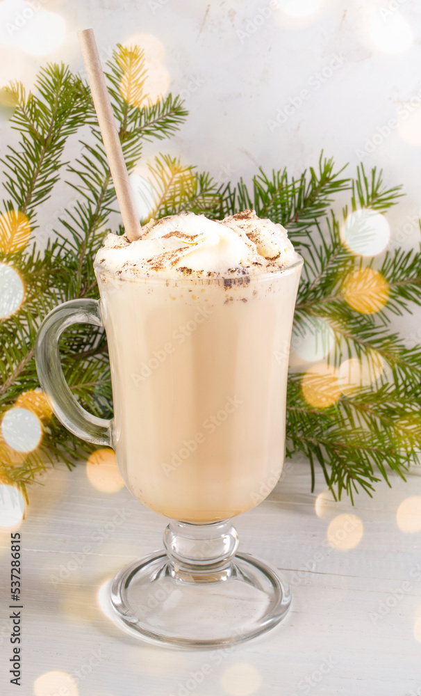 Traditional dairy drink with eggs eggnog in glass with fir branches with Christmas lights on white. Traditional dairy drink with eggs eggnog in glass with fir branches with Christmas lights on white.