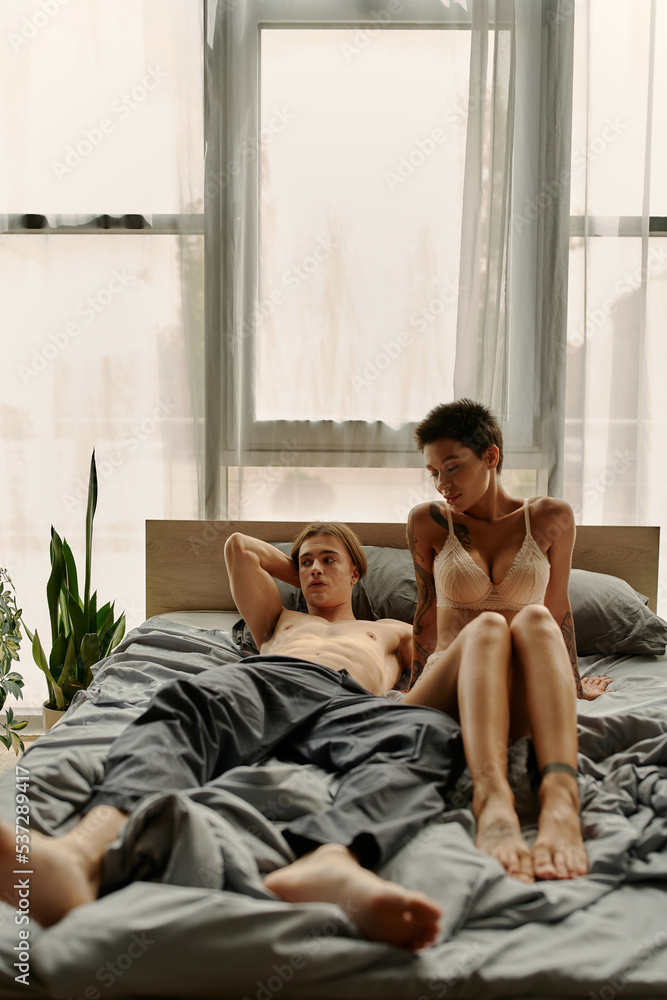 Shirtless man in pajama pants lying near sexy girlfriend on bed. Shirtless man in pajama pants lying near sexy girlfriend on bed.