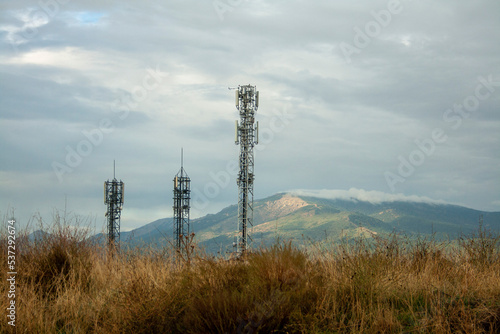 Mobile phone antennas on a stormy day with the mountains in the background