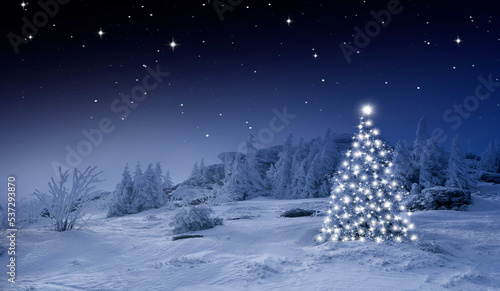 Glänzender Weihnachtsbaum vor einem Blauen Hintergrund im Schnee