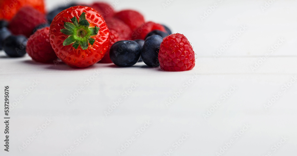 Close-up of strawberry with blueberries and raspberries over white background, copy space Close-up of strawberry with blueberries and raspberries over white background, copy space