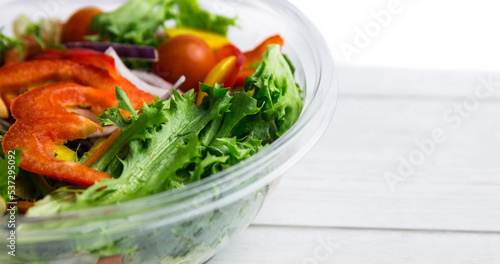 High angle close-up of fresh vegetable salad in glass bowl over wooden table, copy space