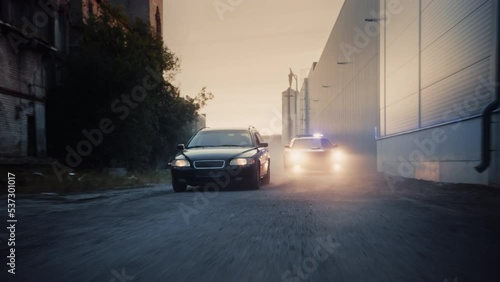 Traffic Patrol Car in Pursuit of Criminal Vehicle. Police Officers in Squad Car Chasing Suspect on Industrial Road, Sirens Blazing, High Speed. Stylish Cinematic Dolly Zoom Shot of Action Scene photo