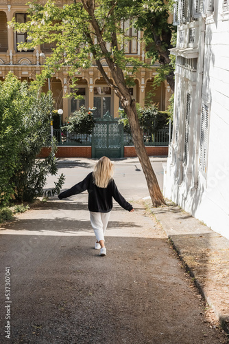 back view of young blonde woman in trendy outfit walking on street in turkey. photo