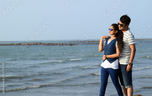 Mid long shot of asian young couple standing at the sea shore having a romantic time enjoying the beauty of nature.