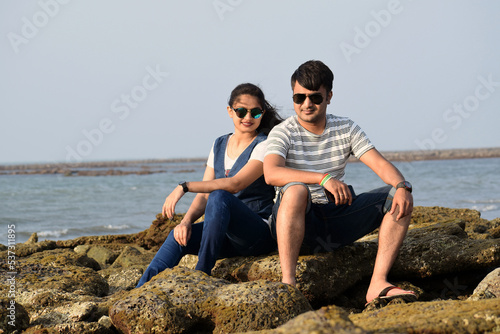 Asian newly married couple sitting on the coral of a sea beach passing romantic time.