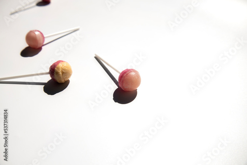Pink lolipop candies lie on a white background. Side view