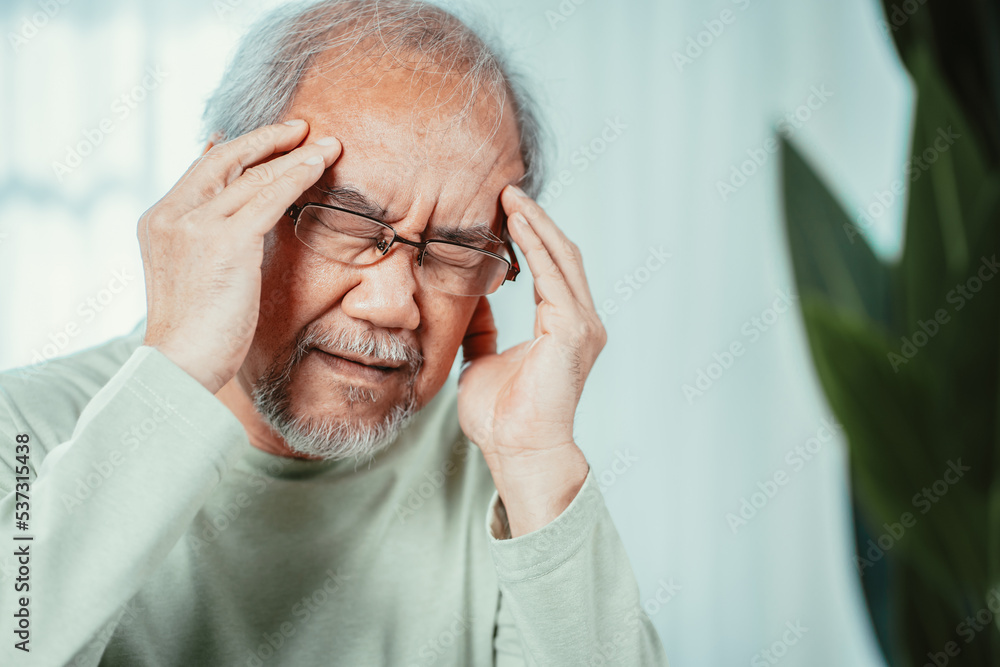 Closeup of Asian Senior elderly old man feel headache suffering and migraine in living room at home. Stressed mature male hurt mental health care and insurance concept. Closeup of Asian Senior elderly old man feel headache suffering and migraine in living room at home. Stressed mature male hurt mental health care and insurance concept.