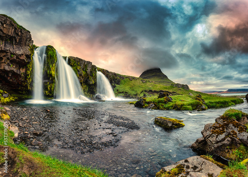 Landscape of sunset over Kirkjufell mountain with Kirkjufellsfoss waterfall and colorful pileus cloud on summer at Iceland