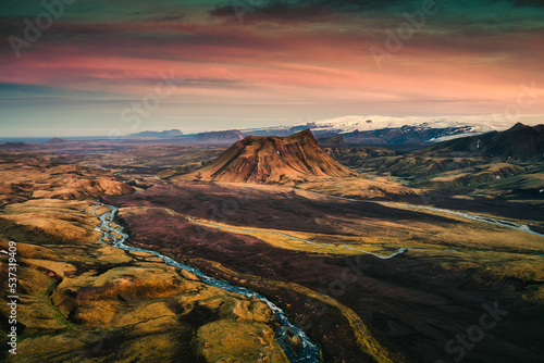 Extinct volcanic crater among the lava field and river flowing through at the sunset in Icelandic Highlands on summer