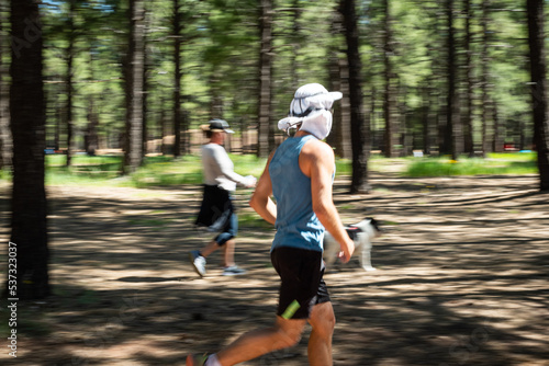 Man, woman, and dog running in the Fort Tuthill County Park in Flagstaff, Arizona, USA.
