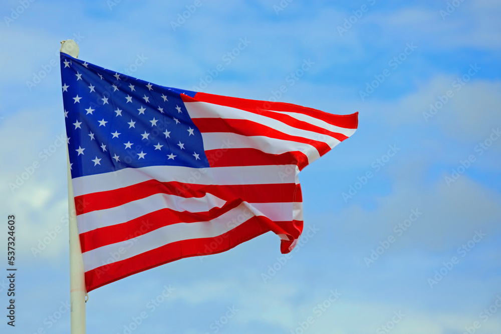 American Flag waving in the blue sky with some clouds American Flag waving in the blue sky with some clouds