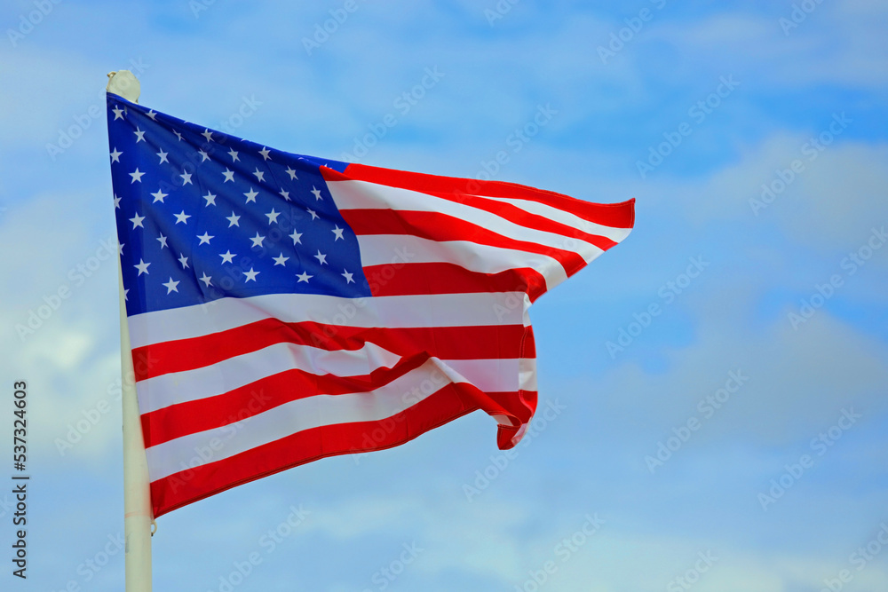 American Flag waving in the blue sky with some clouds