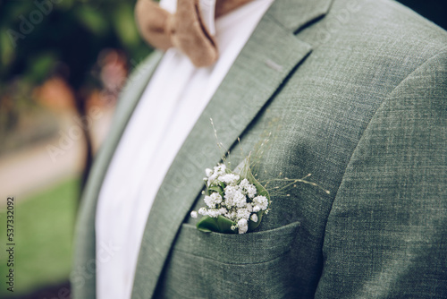 Green groom suit. Groom with beautiful bow tie and elegant linen suit