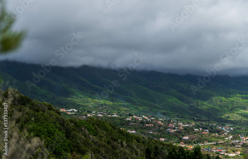 Village in the background with incredible landscape of mountains full of green colour and a sky covered by clouds.