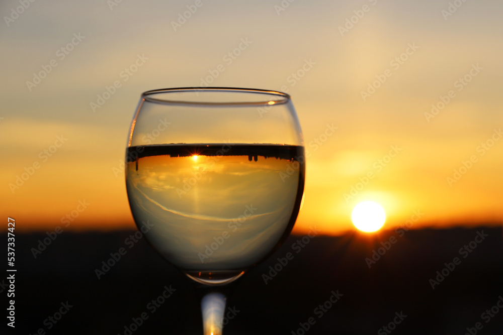 Wine glass with city buildings reflection on sunset sky background. Concept of celebration, wine industry