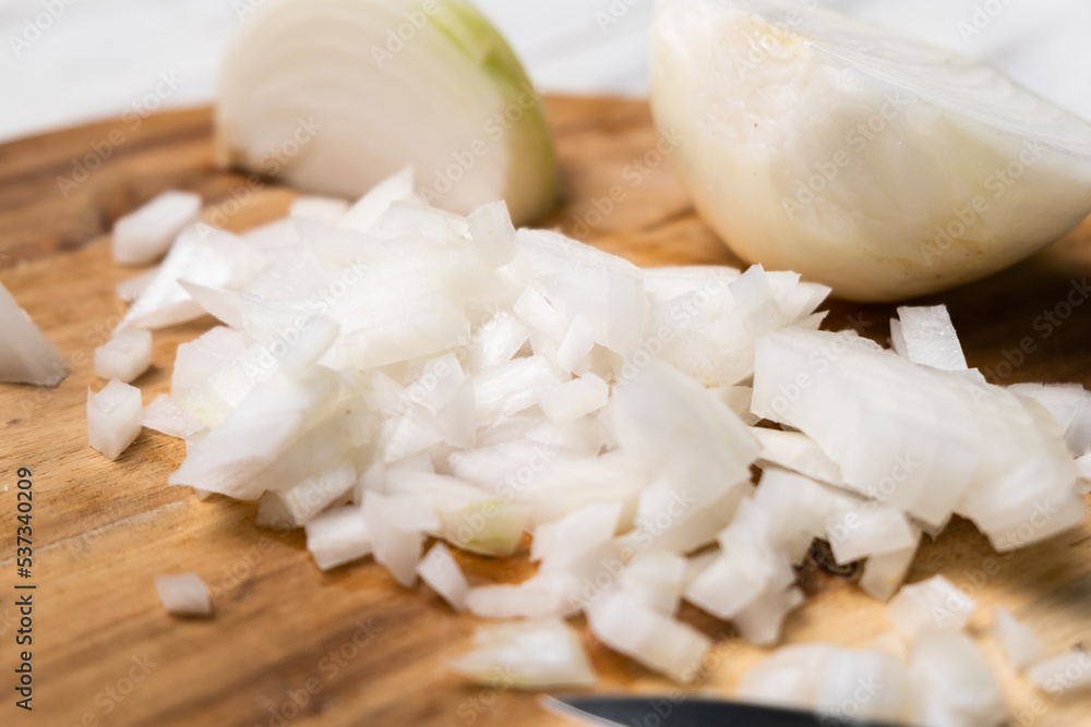 Diced onion on a wooden cutting board. Sliced white onion. Diced onion on a wooden cutting board. Sliced white onion.