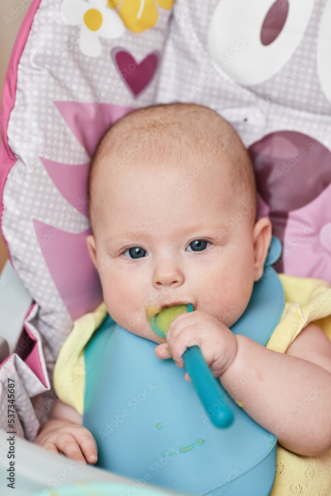 cute baby girl eating with spoon in kitchen cute baby girl eating with spoon in kitchen