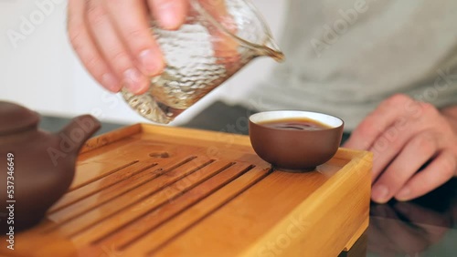 close-up of a male hand pouring tea into a clay bowl. traditional chinese tea ceremony. 4k. slow motion photo