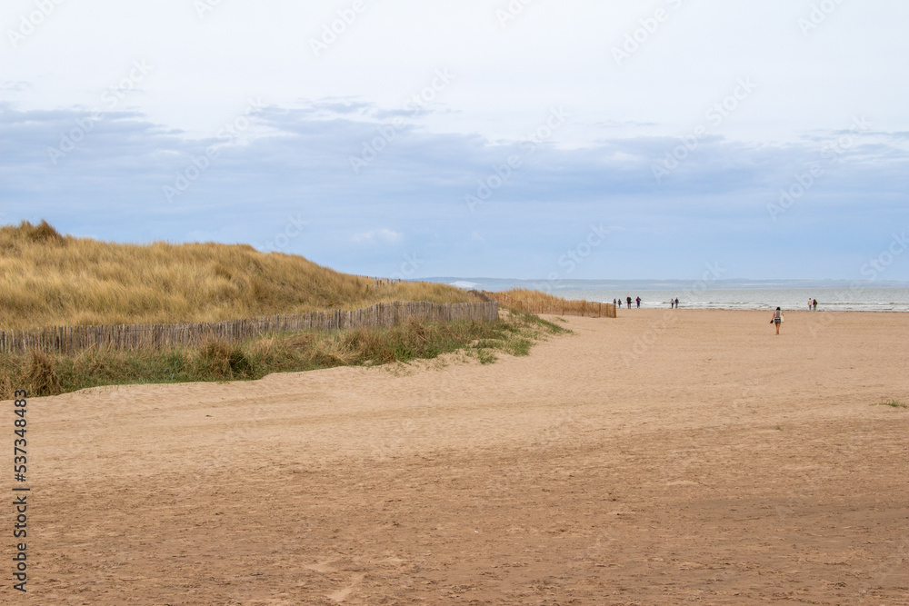 Landscape view of a sandy beach along the North Sea on the east coast of Scotland, next to St. Andrews, with unidentifiable people.