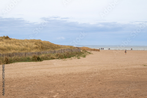 Landscape view of a sandy beach along the North Sea on the east coast of Scotland, next to St. Andrews, with unidentifiable people.