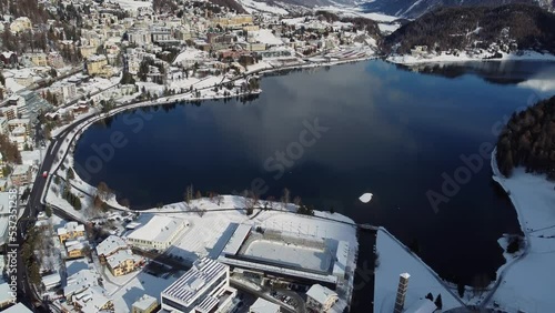 St Moritz, Switzerland: Aerial drone footage of the Saint Moritz ski resort village and lake on a sunny winter day in the Engadine valley in Canton Graubunden in the Swiss alps, with tilt up motion. photo