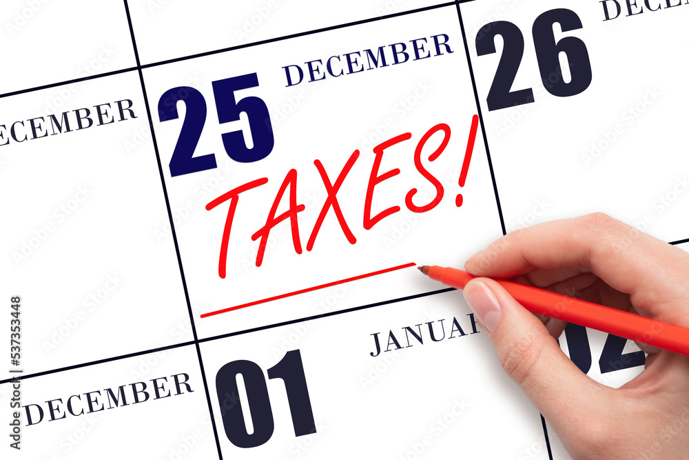 Hand drawing red line and writing the text Taxes on calendar date December 25. Remind date of tax payment Hand drawing red line and writing the text Taxes on calendar date December 25. Remind date of tax payment
