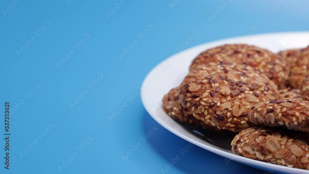 Oatmeal Cookies With Sesame Seeds On A Plate On A Blue Background. Panning Dolly Slider Shot. 60 FPS, 4k, ProRes Oatmeal Cookies With Sesame Seeds On A Plate On A Blue Background. Panning Dolly Slider Shot. 60 FPS, 4k, ProRes