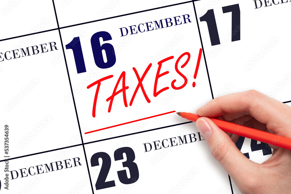 Hand drawing red line and writing the text Taxes on calendar date December 16. Remind date of tax payment Hand drawing red line and writing the text Taxes on calendar date December 16. Remind date of tax payment