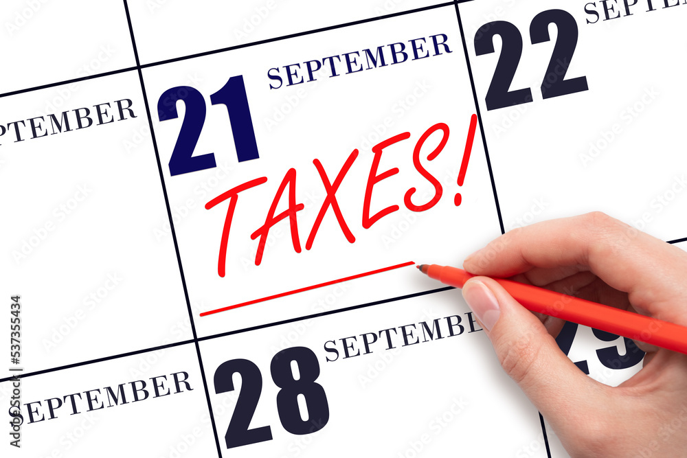 Hand drawing red line and writing the text Taxes on calendar date September 21. Remind date of tax payment Hand drawing red line and writing the text Taxes on calendar date September 21. Remind date of tax payment