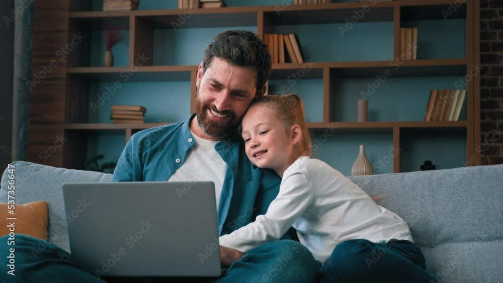 Dad man and little beautiful girl child kid watch video online on laptop lovely caucasian family laugh spend restful time together enjoy weekend at home use modern tech make internet order shopping