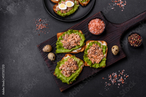 Delicious fresh sandwiches with toast, canned salmon, salad and quail eggs