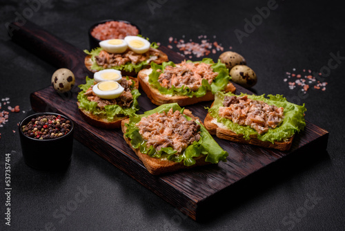 Delicious fresh sandwiches with toast, canned salmon, salad and quail eggs